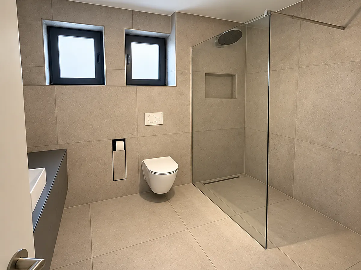 Saniertes Bad mit großen Fliesen, Wand-WC und bodengleicher Dusche