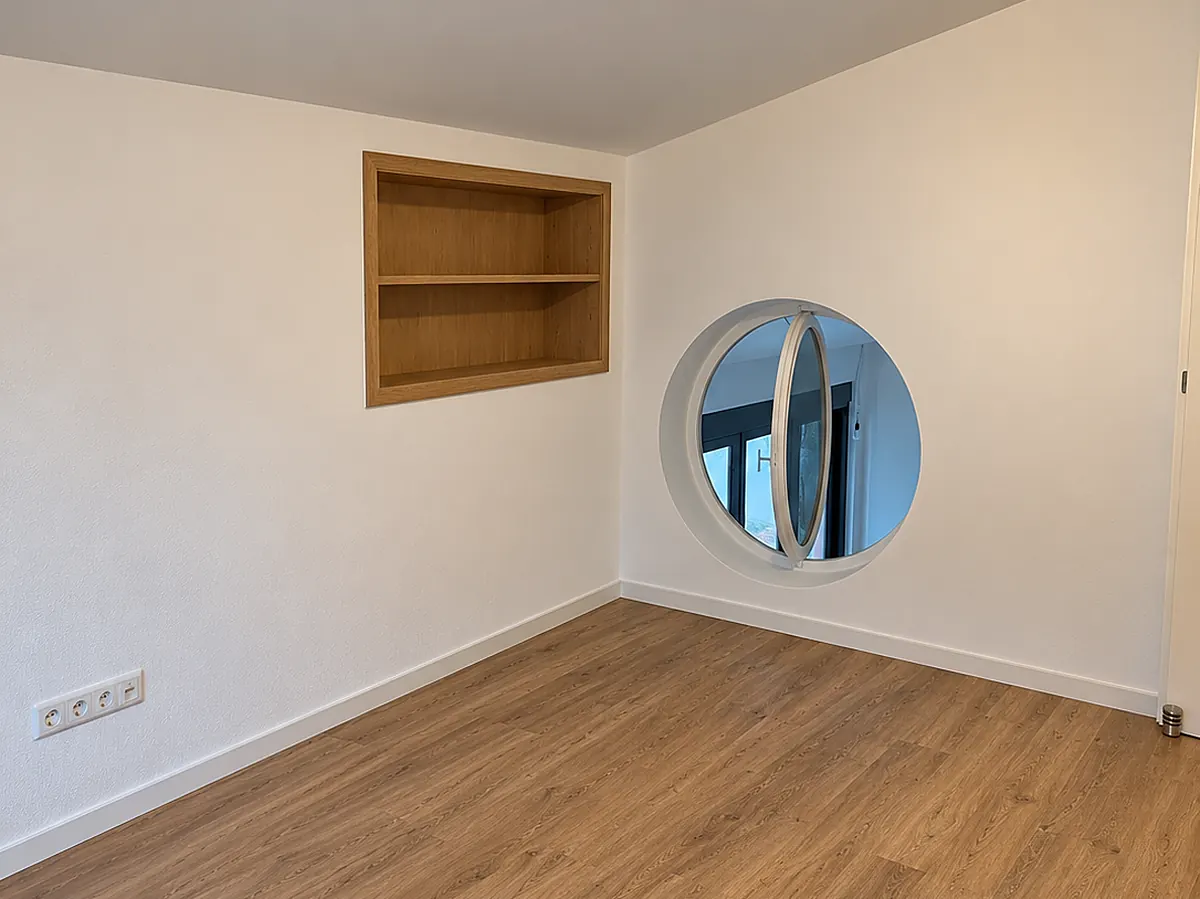 Zimmer mit neuem Boden in Holzoptik, rundem Fenster und Wandnische