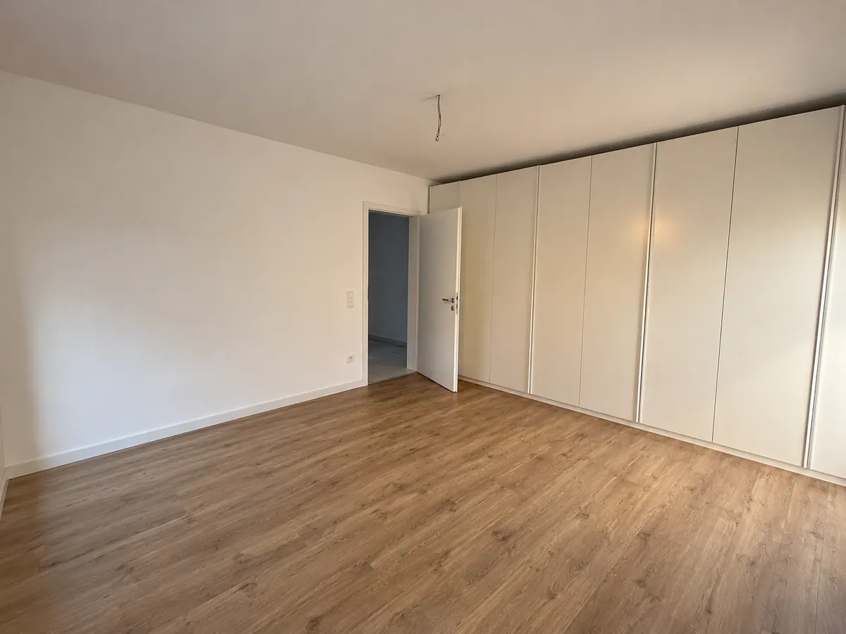 Frisch gestrichenes Schlafzimmer mit hellen Wänden und Holzboden